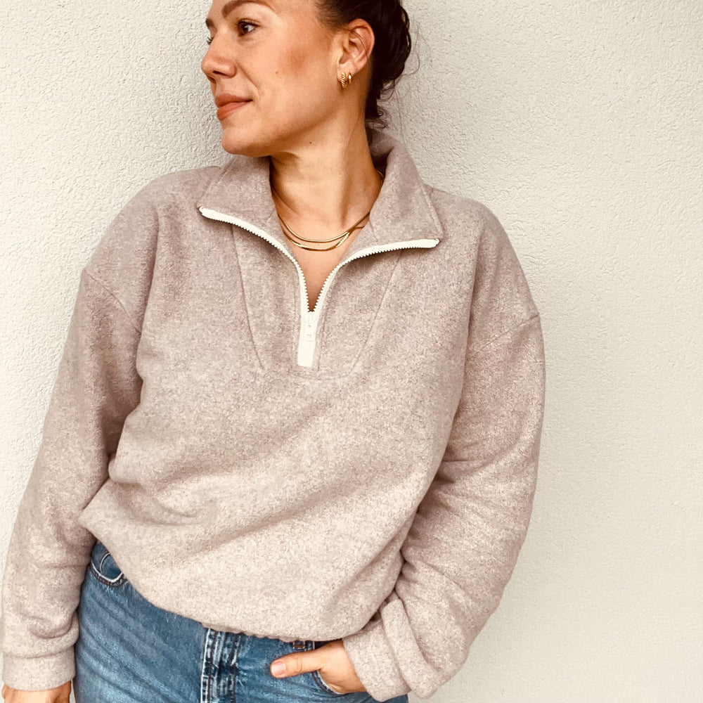 Woman wearing the Neve Sweater sewing pattern from Sew.lala Patterns on The Fold Line. A top pattern made in sweatshirt, French terry, or teddy fabric, featuring a relaxed fit, dropped shoulders, collar, quarter-zip front, long sleeves, and elasticated hem.