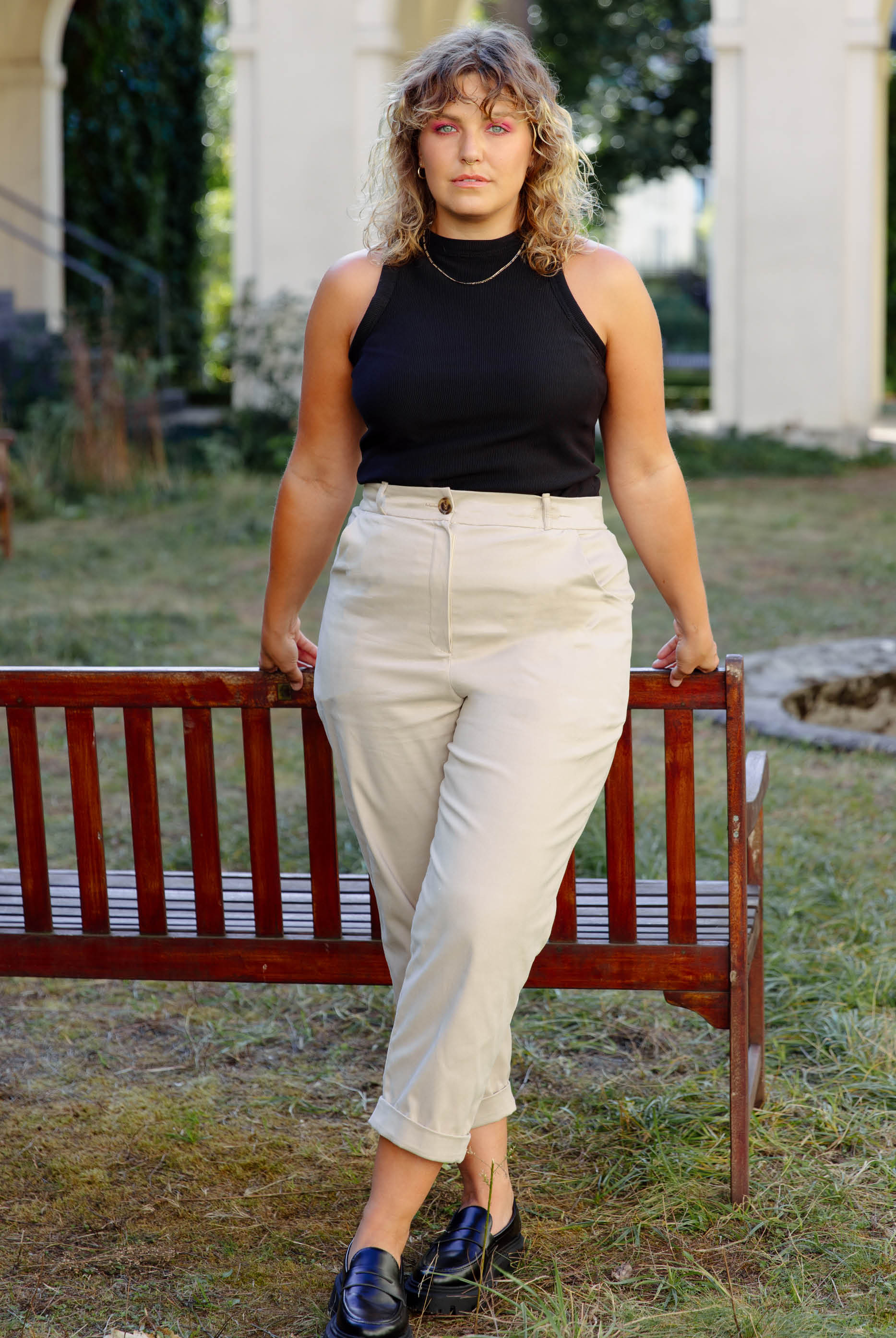 Woman wearing the Nicki Pants sewing pattern from JULIANA MARTEJEVS on The Fold Line. A pants pattern made in twill fabric, featuring a tailored fit, front pockets, back welt pockets, belt loops, double folded cuffs, and a cropped length.