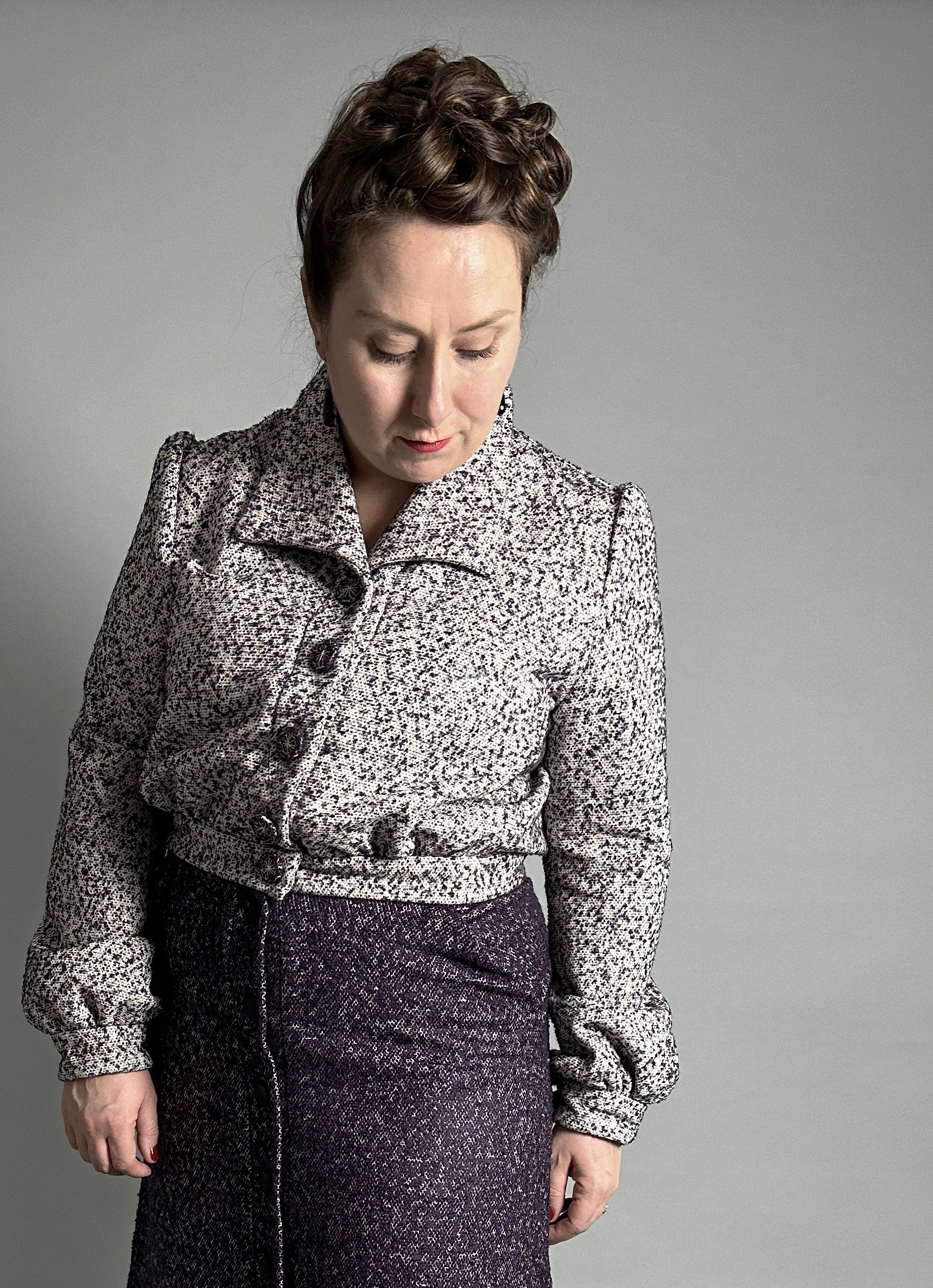 Woman wearing the No. 31 Firenze Jacket sewing pattern from How to Do Fashion on The Fold Line. A 1940s-inspired jacket pattern made in cotton, silk, wool, viscose, cupro, linen, or polyester fabric, featuring a wide collar, front button placket, back yoke, long sleeves, waistband, and cropped length.