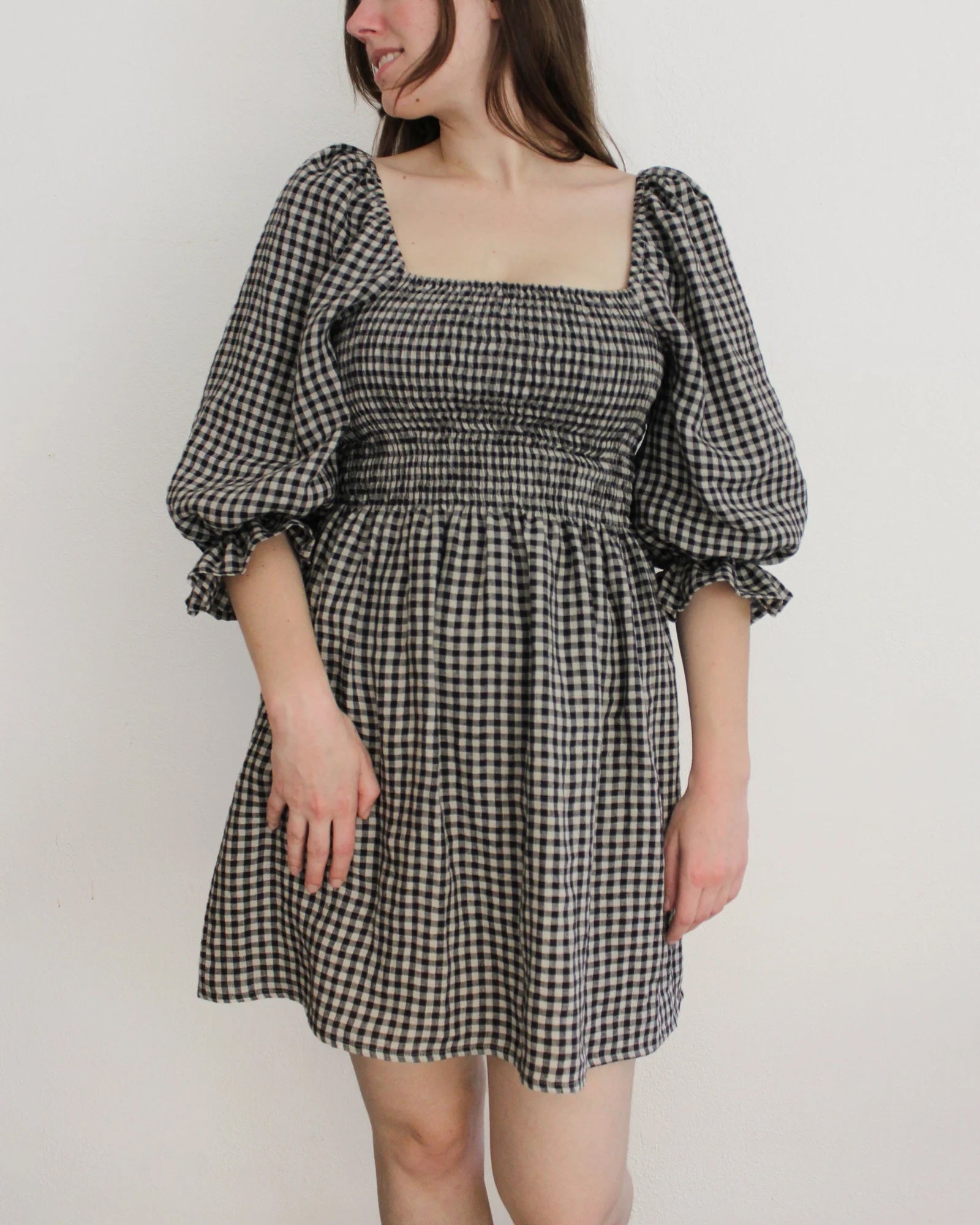 Woman wearing the Nova Dress sewing pattern from Oh Me Oh My Sewing on The Fold Line. A dress pattern made in voile, lawn, double or single gauze, quilting cotton, or washed linen fabric, featuring a square neckline, shirred bodice, elbow-length puff sleeves, and mini length.