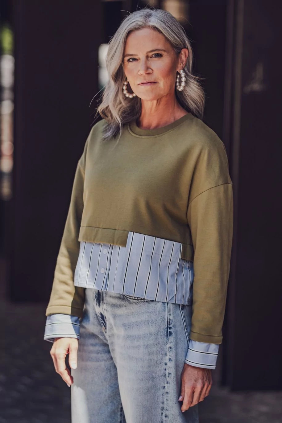 Woman wearing the Ollie Sweater sewing pattern from Fibre Mood on The Fold Line. A sweater pattern made in sweatshirt, French terry, ponte Roma, or neoprene and poplin or cotton twill fabric, featuring a boxy shape, round neck, long sleeves, shirt cuffs, and patch pocket.