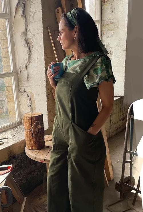Woman wearing the Osborn Dungarees sewing pattern from Sew Different on The Fold Line. A jumpsuit pattern made in denim, wool, heavy cotton, heavy linen, or corduroy fabric, featuring wide straps, large pockets, wide cropped legs, and a zip at the back.
