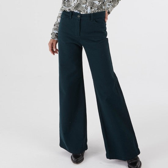 Woman wearing the Pénélope Pants sewing pattern from Coralie Bijasson on The Fold Line. A retro jeans pattern made in stretch denim, stretch corduroy, or stretch cotton satin fabric, featuring a high waist, fly front, back yoke, and flared leg.