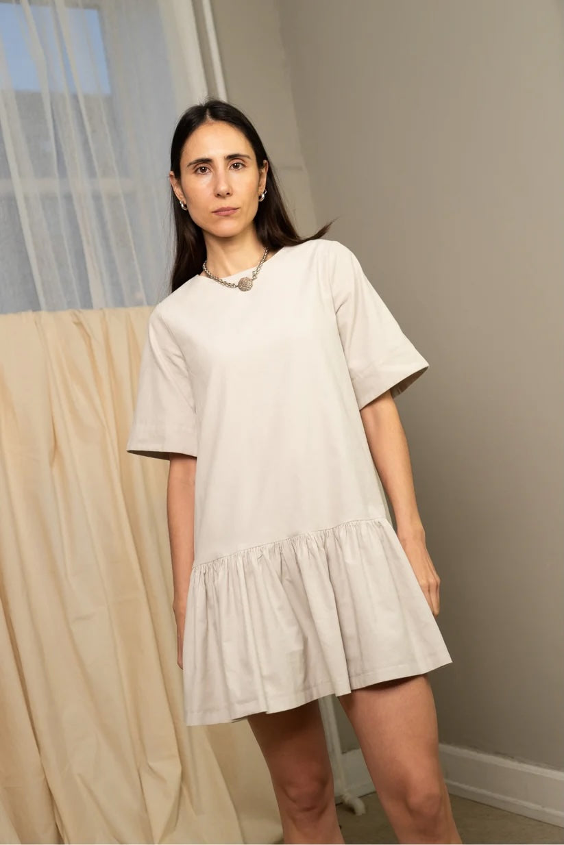Woman wearing the Ruffle Dress & Big T Sleeve sewing pattern bundle from Puff and Pencil on The Fold Line. A dress pattern made in poplin, woven viscose, linen, lightweight denim, lightweight wool, seersucker, cotton satin, jacquard, or cotton twill fabric, featuring a round neckline, short sleeves, gathered hem ruffle, and mini length.