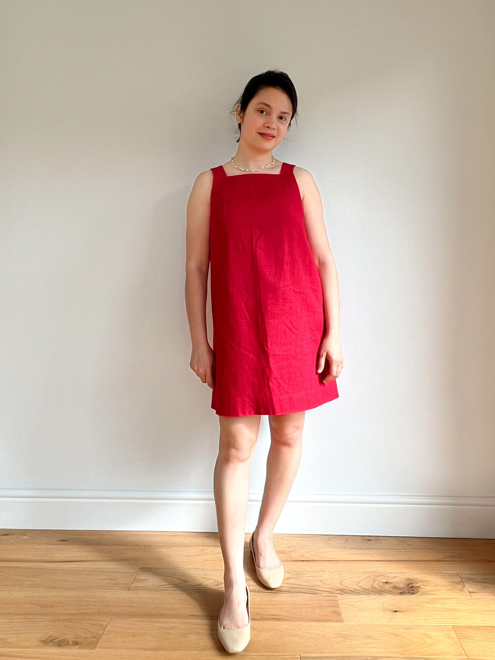 Woman wearing the Sabrina Dress sewing pattern from Bella Loves Patterns on The Fold Line. A shift dress pattern made in linen, chambray, lightweight denim, or cotton fabric, featuring a relaxed fit, high square neckline in front, V-neckline in back, wide straps, and mini length.