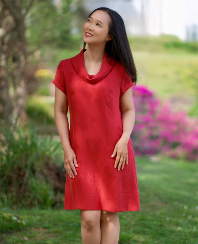 Woman wearing the Simien Dress sewing pattern from Itch to Stitch on The Fold Line. A dress pattern made in viscose, rayon, bamboo, lyocell, or modal blend fabric, featuring princess seams, a cowl neck, short sleeves, pockets, and knee length.