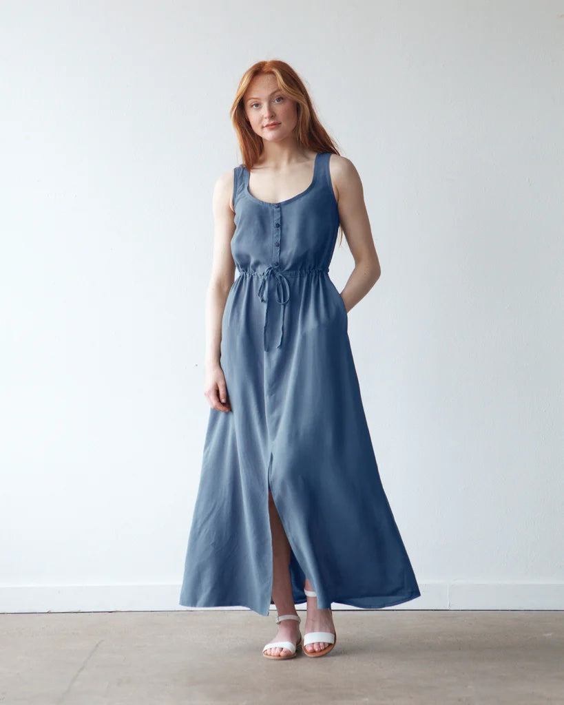 Woman wearing the Southport Dress sewing pattern from True Bias on The Fold Line. A sleeveless dress pattern made in cotton voile, rayon challis, crepe de chine, or lightweight linen fabric, featuring a button opening, drawstring waist, in-seam pockets, and maxi length with a centre front slit.