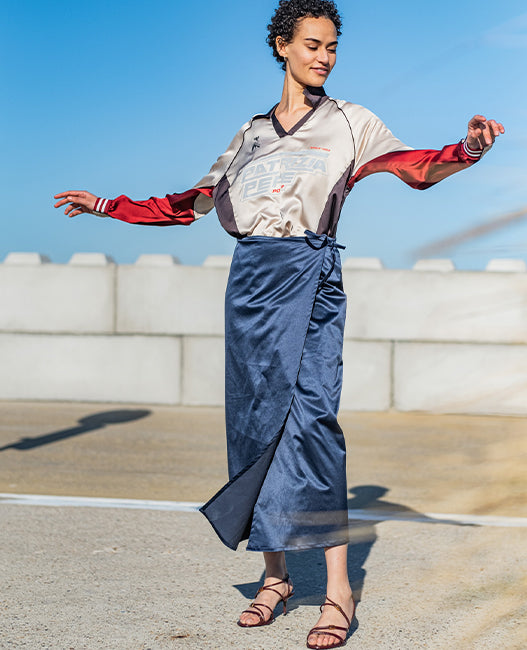 Woman wearing the Tempest Skirt sewing pattern from Fibre Mood on The Fold Line. A wrap skirt pattern made in organza, lace, crepe, lyocell, satin, chambray, linen, seersucker, cotton voile, muslin, crepon, or poplin fabric, featuring a straight cut and midi length.