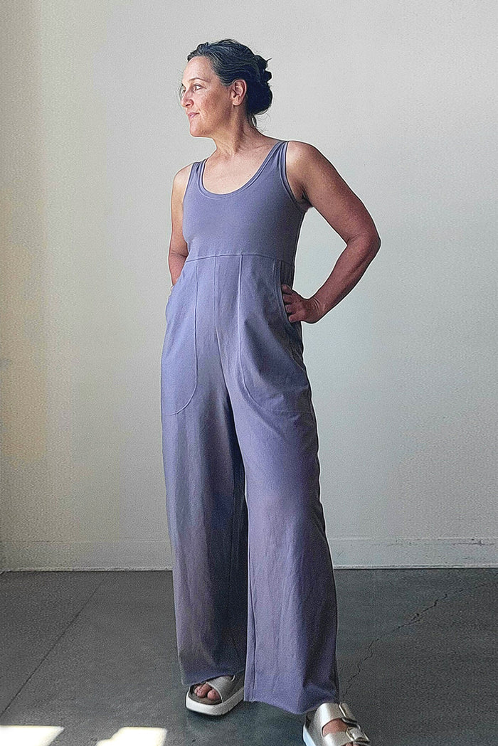 Woman wearing the Tumalo Knit Jumpsuit sewing pattern from Sew House Seven on The Fold Line. A sleeveless jumpsuit pattern made in knit fabric, featuring a tank-style top, high almost-empire waist, deep pockets, and straight wide legs.