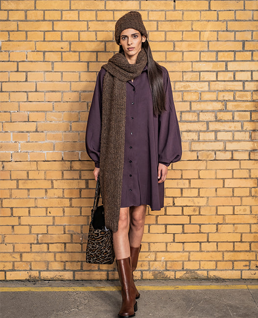 Woman wearing the Ursula Dress sewing pattern from Fibre Mood on The Fold Line. A shirt dress pattern made in crepe, viscose, chambray, poplin, or fine rib velvet fabric, featuring a loose oversized fit, collar, button front, long voluminous sleeves gathered into cuffs, and an above knee length.