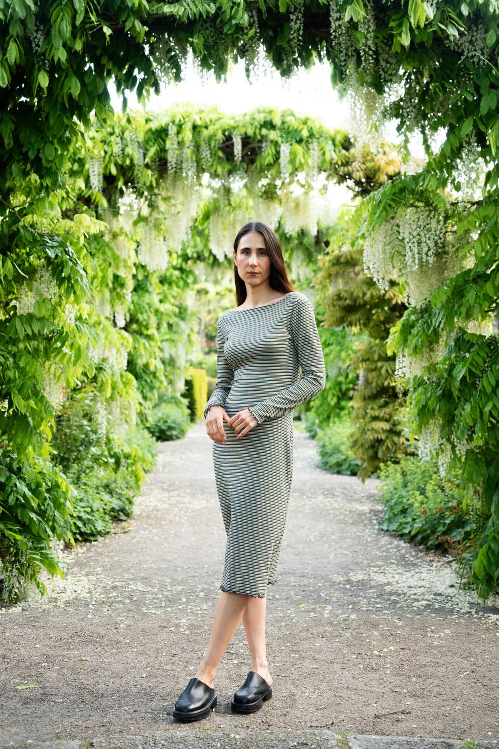 Woman wearing the Wavy Hem Dress & Slim Sleeve sewing pattern bundle from Puff and Pencil on The Fold Line. A dress pattern made in stretch mesh, fine cotton rib, or jersey fabric, featuring a body-hugging fit, boat neckline, long sleeves, and wavy hem.