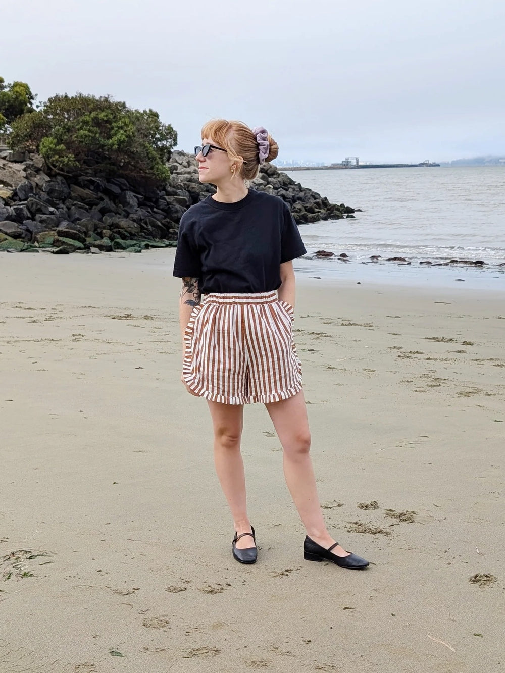 Woman wearing the Willa Shorts sewing pattern from Spaghetti Western Sewing on The Fold Line. A shorts pattern made in cotton lawn, voile, or poplin fabric, featuring a high rise, elastic waist, curved split side seam, pockets, and ruffle hem.