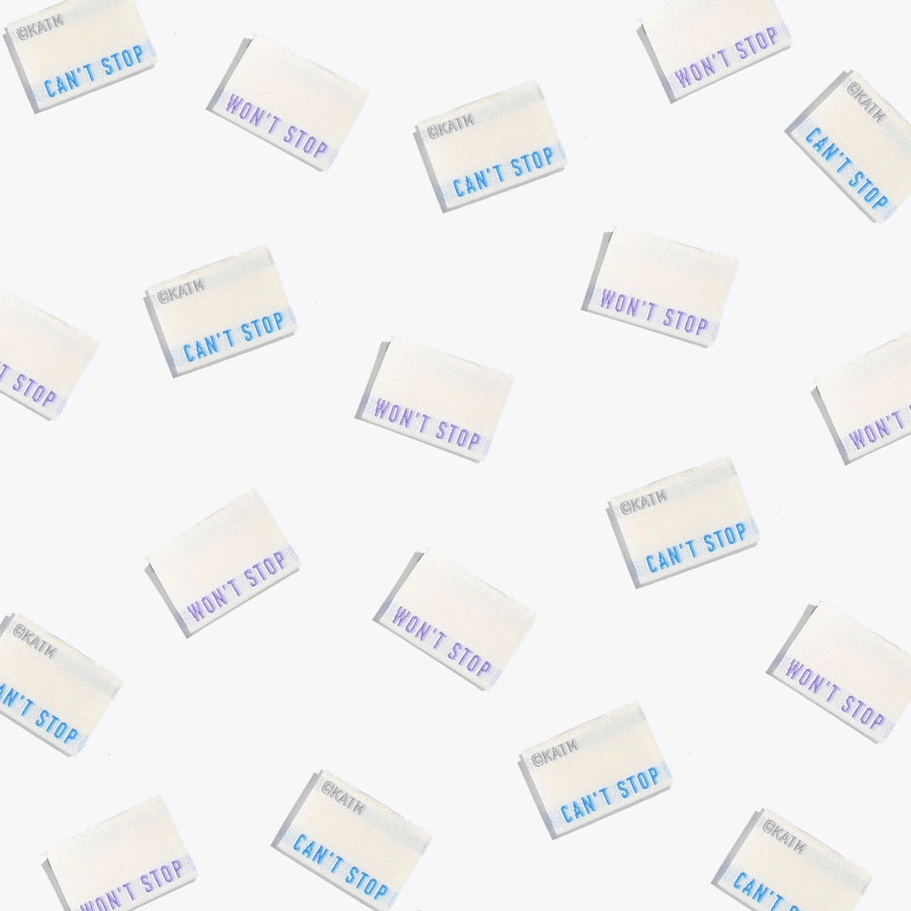 Photo showing 'Can’t Stop Won’t Stop’ Labels from Kylie & The Machine on The Fold Line. A washable, durable, and non-scratchy label. Included are, 6 woven labels with a mid-blue or mauve lettering on a cream background. They are all ready to be sewn into