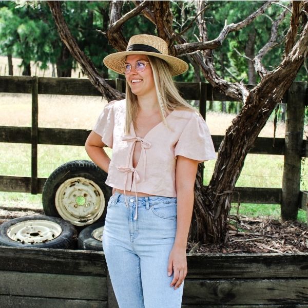 Woman wearing the Camille Top sewing pattern by Makyla Creates. A top pattern made in light to medium weight fabrics such as linens, cottons, silk, tencel or rayon fabrics, featuring a cropped length, loose fit, deep V-neck and two functional ties at the