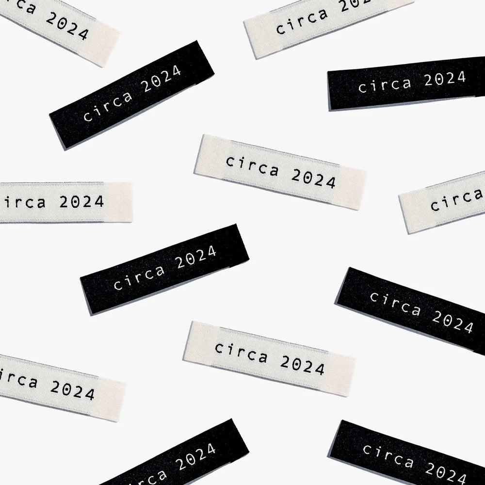 Photo showing 'Circa 2024' Labels from Kylie & The Machine on The Fold Line. A washable, durable, and non-scratchy label. Included are 6 woven labels: 3 x black polyester labels with cream text and 3 x off-white polyester labels with black text. They are