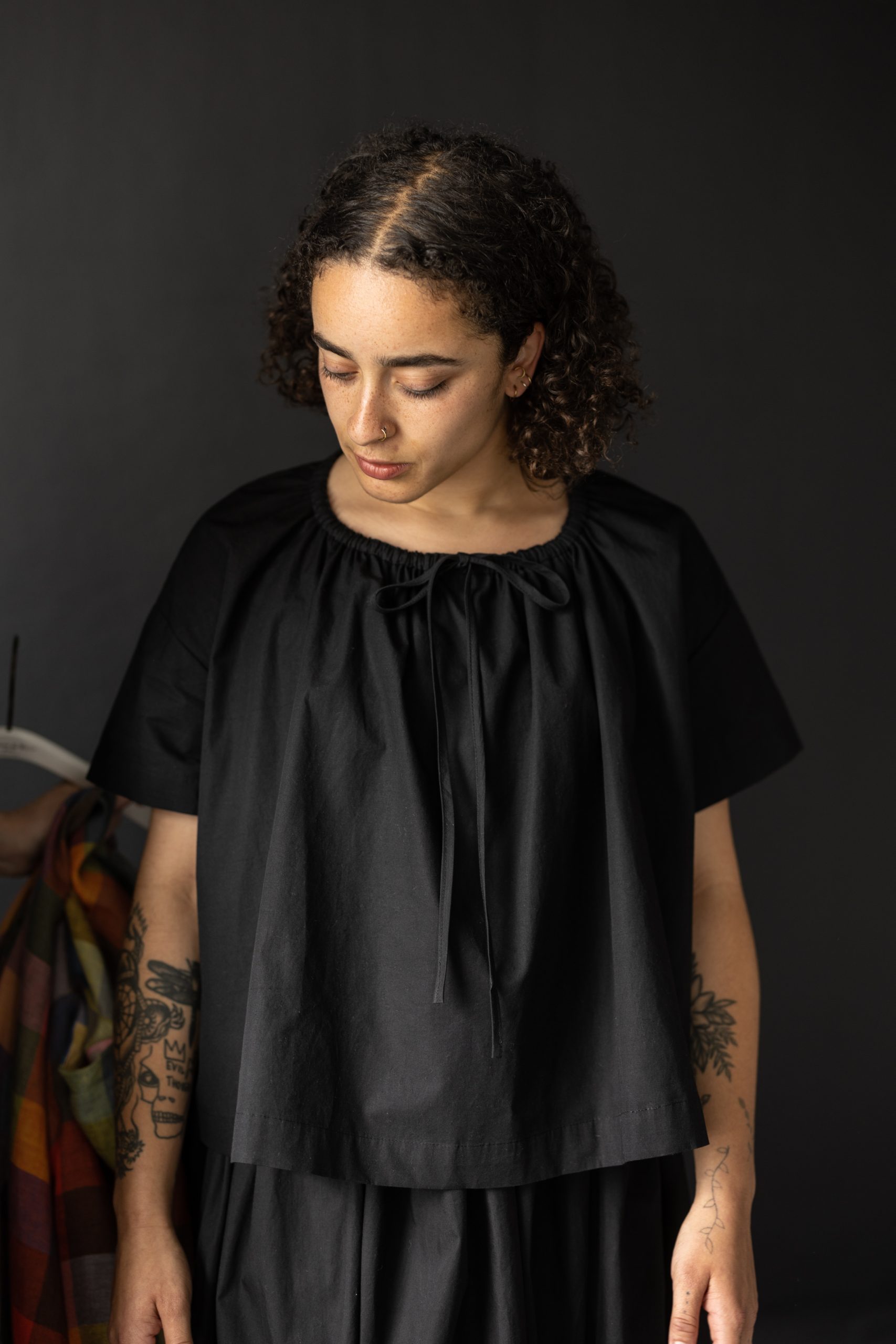 Woman wearing the Clover Top sewing pattern from Merchant & Mills on The Fold Line. A top pattern made in linen, brushed cotton, cotton lawn, cotton poplin, tencel, Indian handlooms, lightweight baby cord or cotton double gauze fabrics, featuring a gather