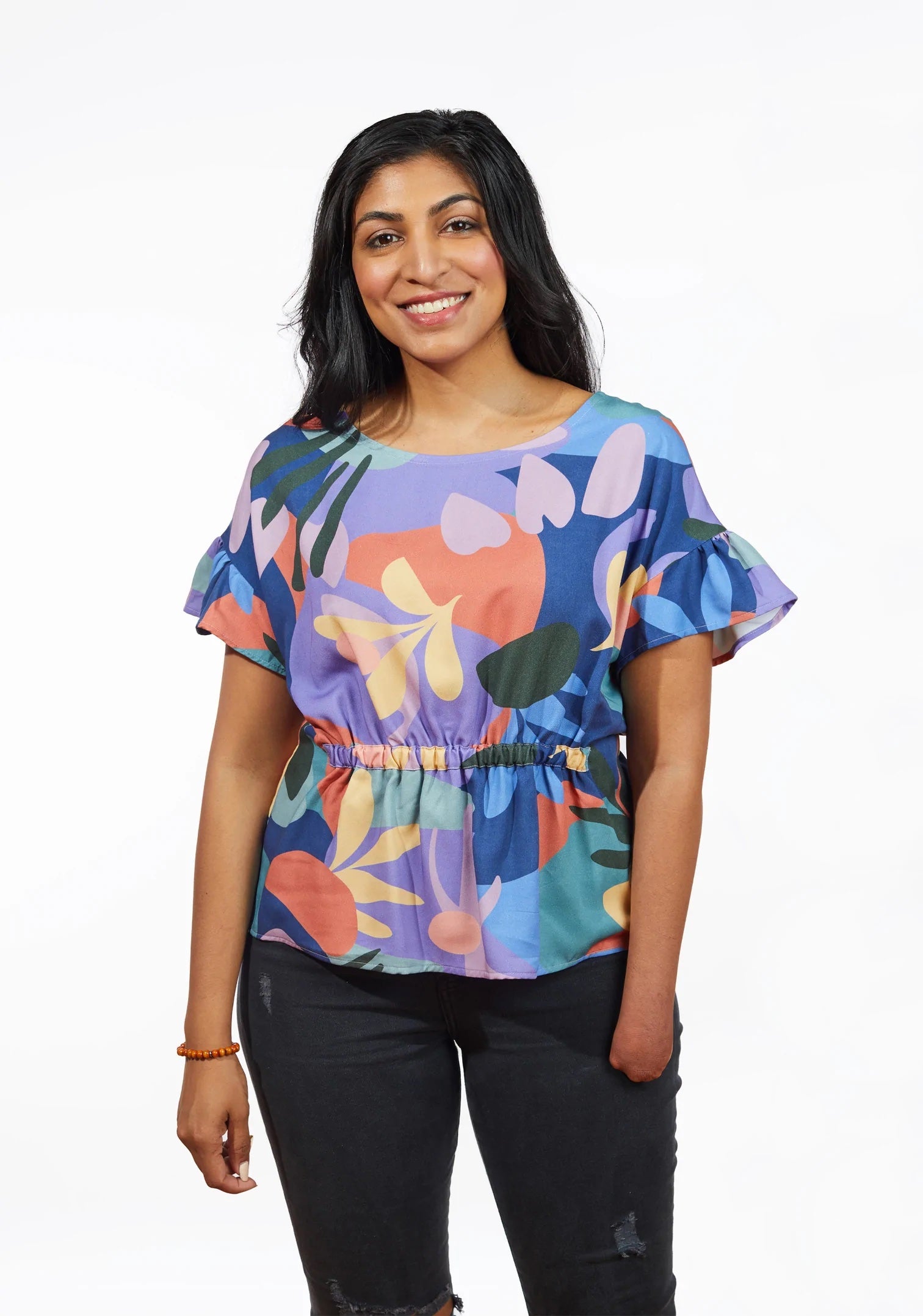 Woman wearing the Corin Top sewing pattern from Grainline Studio on The Fold Line. A top pattern made in double gauze, charmeuse, crepe de chine, rayon or rayon blend fabrics, featuring a ruffled cap sleeve, gathered elastic waist, relaxed fit and scoop n
