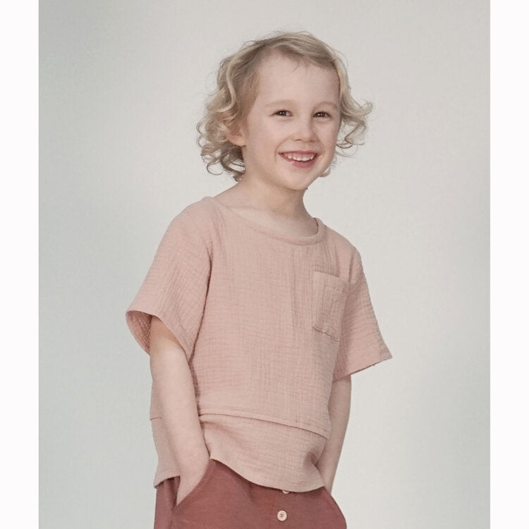 Child wearing the Child Wren Woven Tee sewing pattern from Pattern Paper Scissors on The Fold Line. A T-shirt pattern made in cotton, viscose, denim, double gauze, linen or crepe fabrics, featuring a button-through back, round neck, chest pocket, relaxed