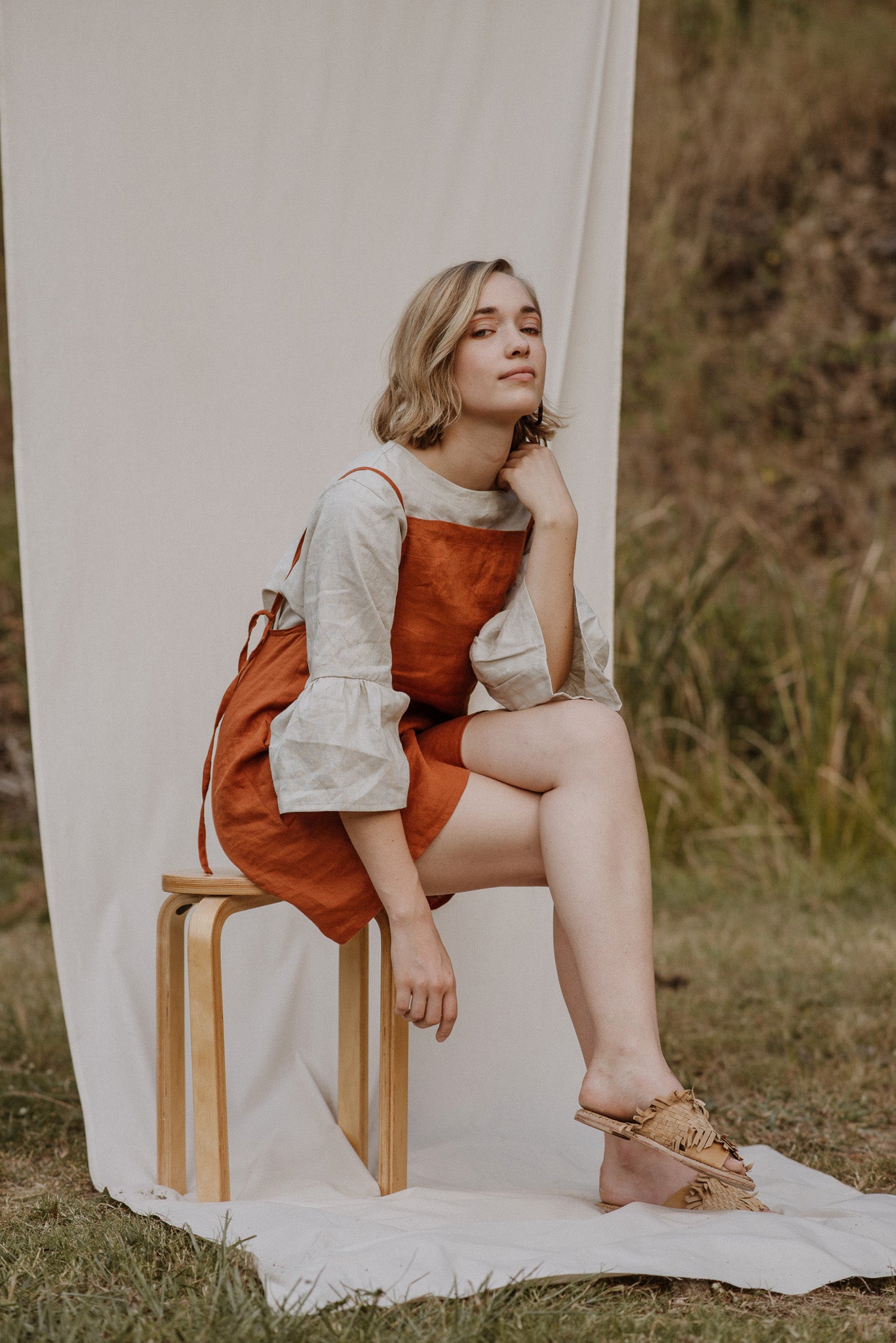 Woman wearing the Bellbird Blouse sewing pattern by Common Stitch. A blouse pattern made in linen fabrics, featuring fluted sleeves, relaxed fit and a bateau neckline.