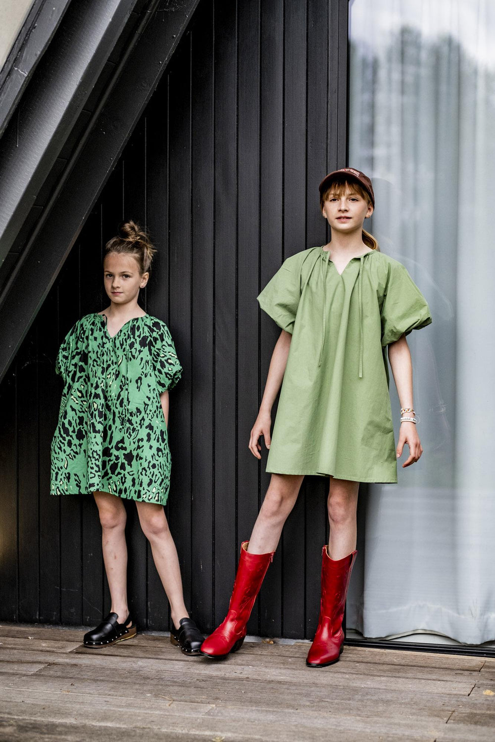 Children wearing the Children's Daisy Dress sewing pattern from Fibre Mood on The Fold Line. A dress pattern made in poplin, batiste, and chambray fabrics, featuring an oversized A-line style, voluminous raglan puff sleeves, gathered and pleated neckline,