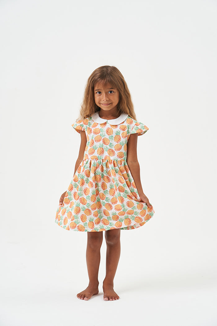 Child wearing the Baby/Child Daisy Dress sewing pattern from Poppy & Jazz on The Fold Line. A dress pattern made in cotton lawn, cotton poplin, linen or broderie anglaise fabrics, featuring a bodice, gathered skirt, cap sleeves, peter pan collar, button o