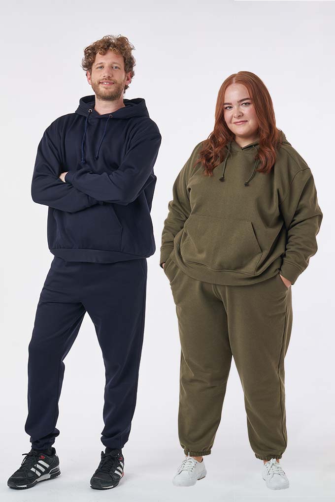 Man and Woman wearing the Unisex Drew Hoodie sewing pattern from Sew Over It on The Fold Line. A unisex hoodie pattern made in cotton sweatshirting, cotton fleece, polar fleece, french terry, ponte di roma and double knit fabrics, featuring a slightly ove