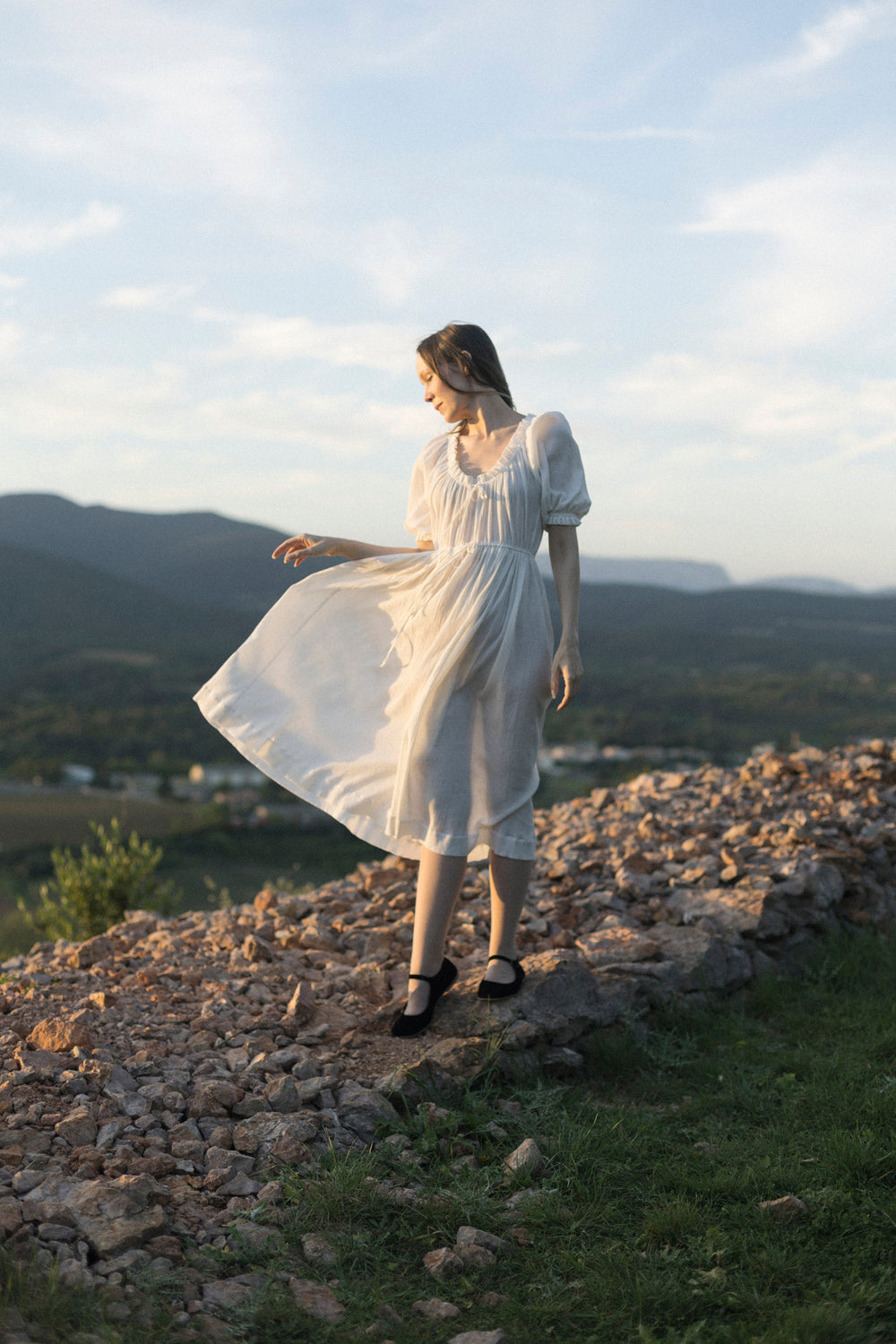 Woman wearing the Eleonora Dress sewing pattern from Silversaga Patterns on The Fold Line. A dress pattern made in cotton voile, cotton lawn, or cotton double gauze fabric, featuring a vintage look, adjustable ties and elastic at the neckline and waist, g