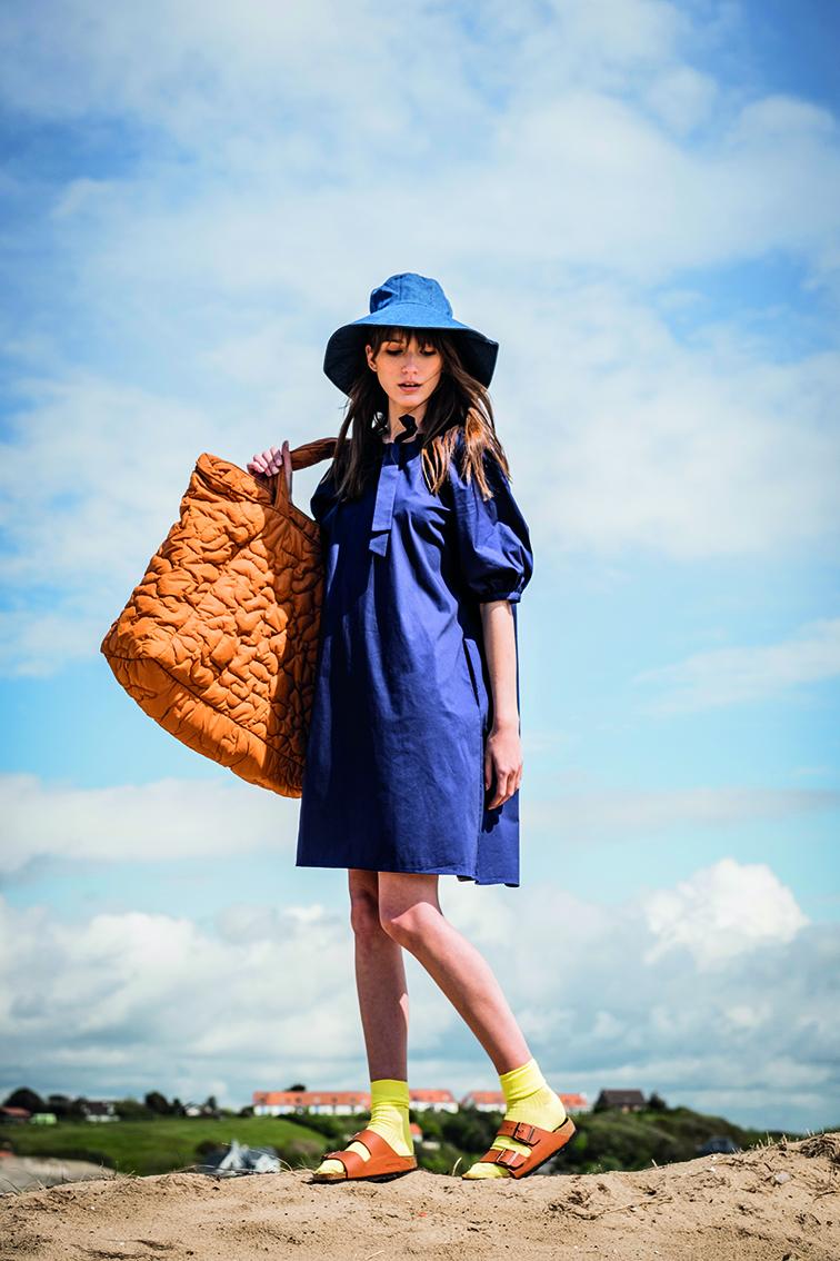 Women wearing the Dolly Dress sewing pattern from Fibre Mood on The Fold Line. A dress pattern made in poplin, batiste, and chambray fabrics, featuring a large neck bow, short puffed raglan sleeves, front and back neck gathers, relaxed fit and above knee