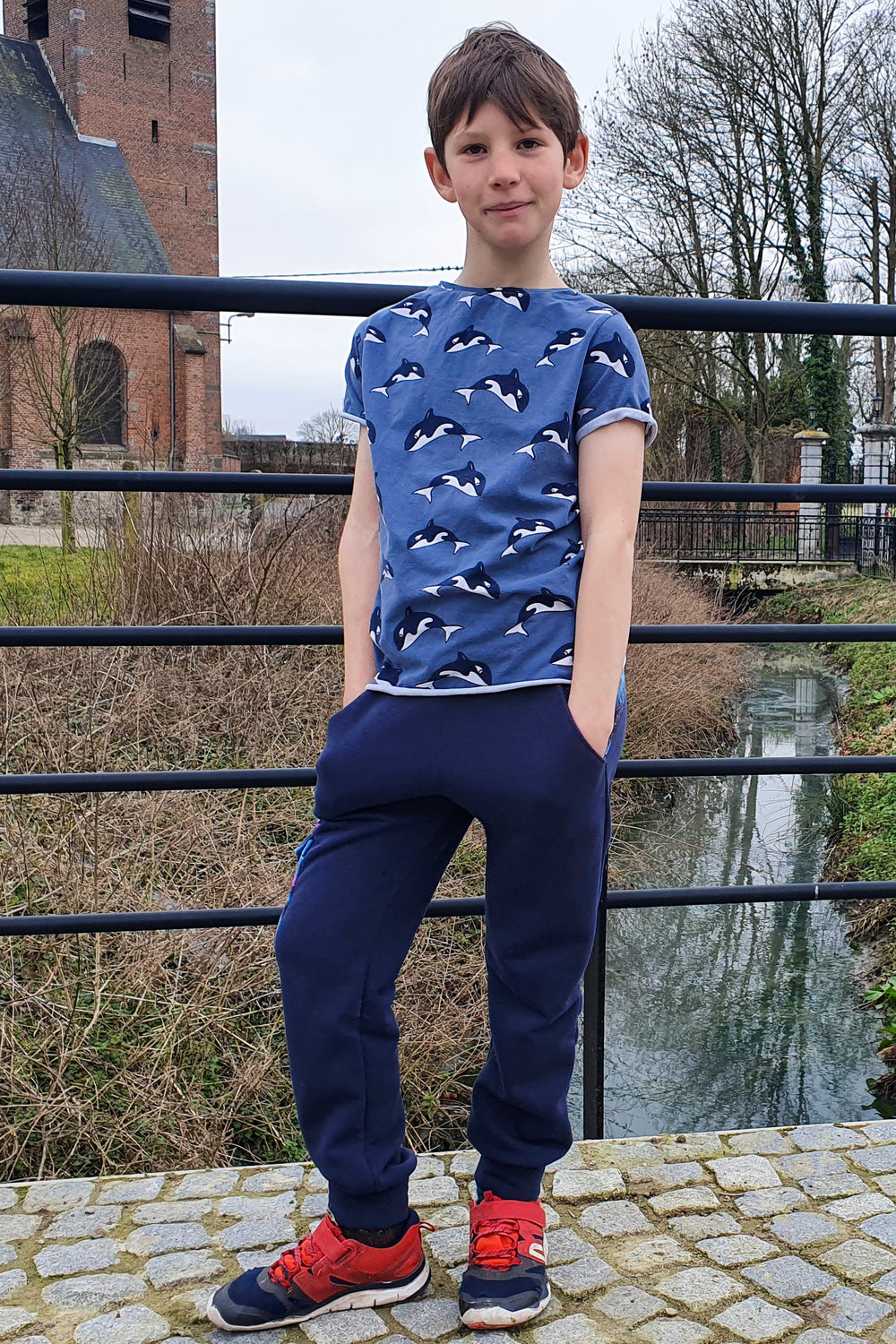 Child wearing the Teen Boys' Field Trip Joggers sewing pattern from Waves & Wild on The Fold Line. A joggers pattern made in stretch knit fabrics, featuring a relaxed fit, hip pockets and elasticated waist.