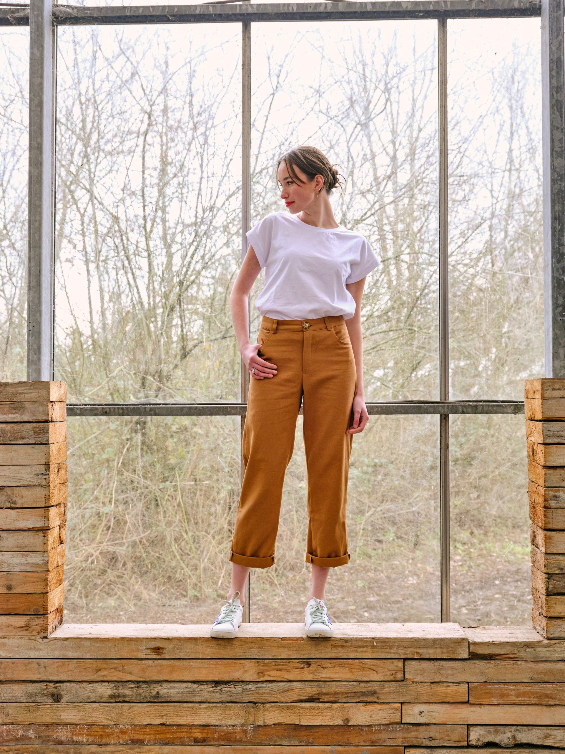 Woman wearing the Frankie Trousers sewing pattern from Atelier Jupe on The Fold Line. A trouser pattern made in cotton, Tencel, linen or corduroy fabrics, featuring a back yoke, front rounded pockets, topstitching, belt loops, fly front zip, and straight