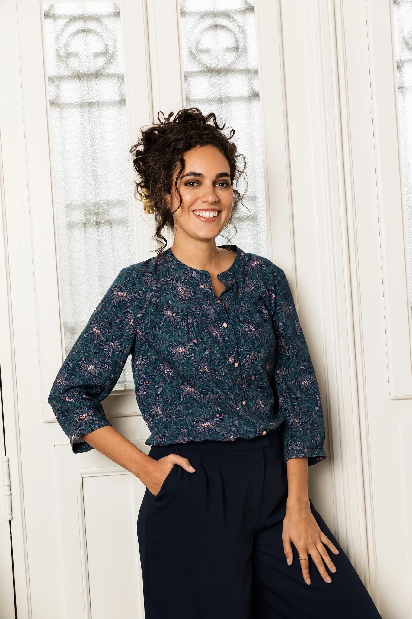 Woman wearing the Frida Blouse sewing pattern from Atelier Jupe on The Fold Line. A blouse pattern made in cotton, viscose, linen or tencel fabrics, featuring a front yoke with gathers, back yoke with inverted pleat, button placket, three-quarter sleeves