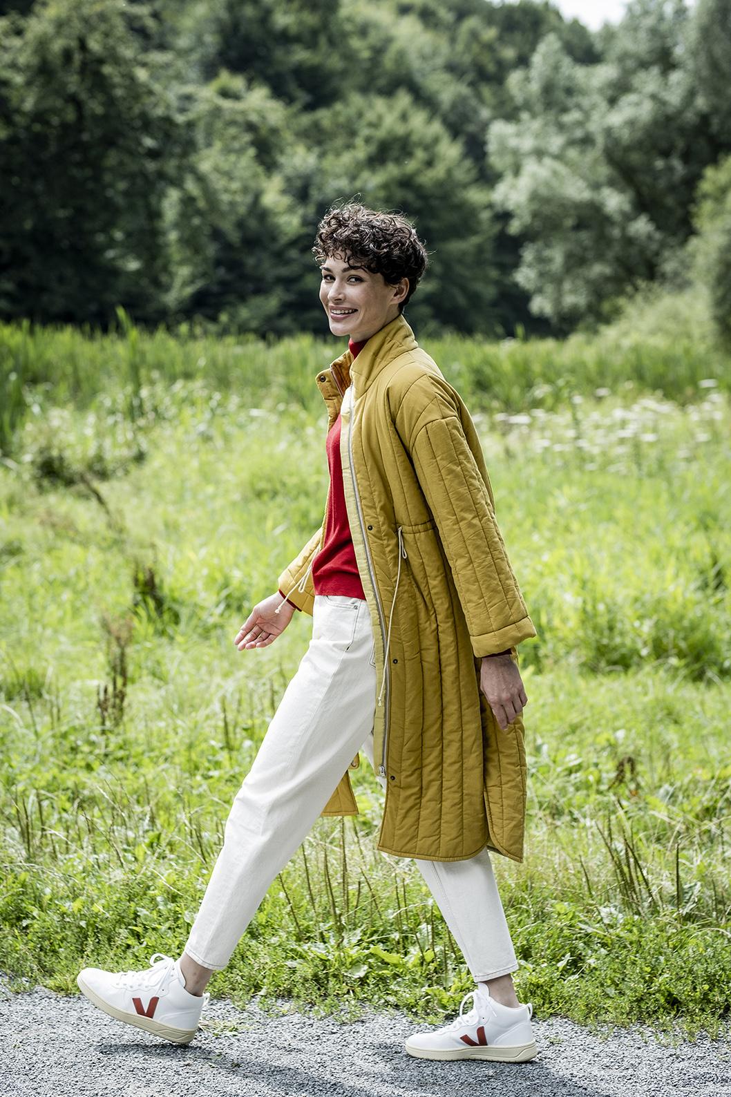 Woman wearing the Giselle Jacket sewing pattern from Fibre Mood on The Fold Line. A jacket pattern made in padded, quilted or matelassé fabrics, featuring, straight full length set-in sleeves, standing collar, zip and stud closure, knee length, side seam