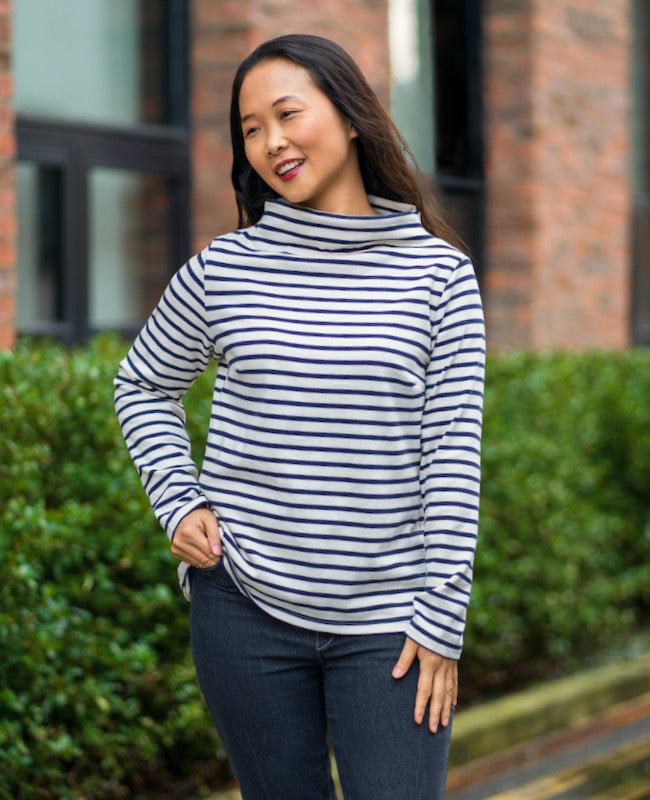 Woman wearing the Gothenburg Top sewing pattern from Itch to Stitch on The Fold Line. A knit top pattern made in ponte, micro fleece, quilted jersey, ottoman rib or scuba fabrics, featuring a relaxed fit, funnel neck, long set-in sleeves, slightly dipped