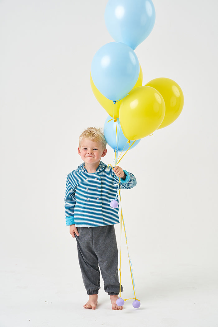 Child wearing the Baby/Child Honeydew Hoodie sewing pattern from Poppy & Jazz on The Fold Line. A hoodie pattern made in cotton jersey, thin ponte di roma, french terry or sweatshirt knits fabrics, featuring a reversible style, lined hood, long sleeves, d