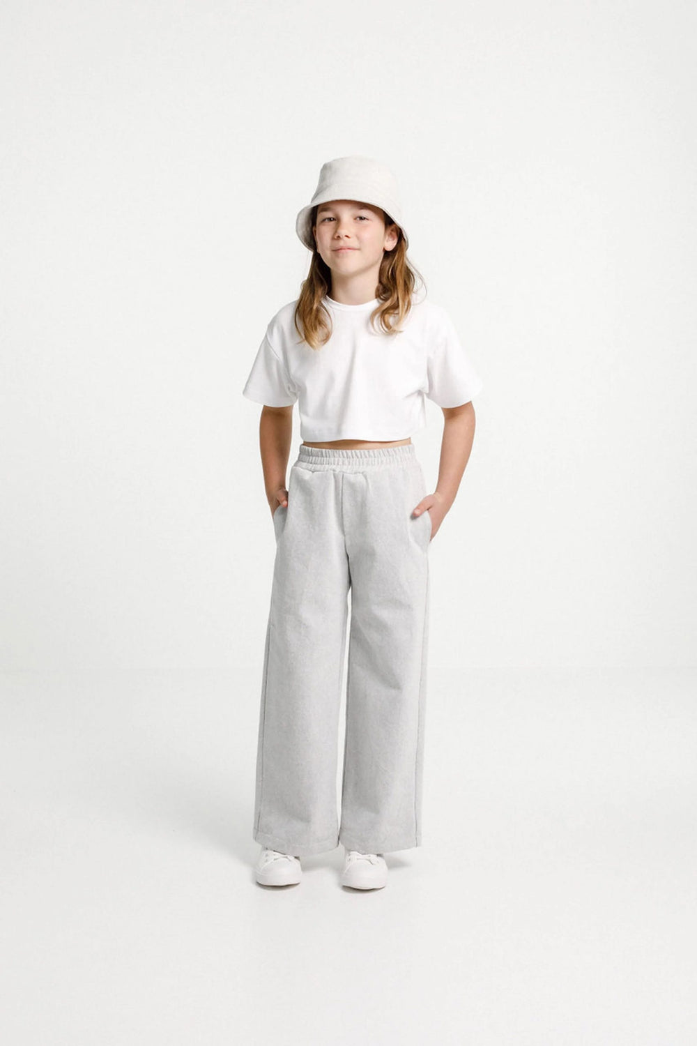 Child wearing the Child/Teen Tula Pants sewing pattern from Papercut Patterns on The Fold Line. A trouser pattern made in light to mid-weight woven or knit fabrics, linen, cotton, sweatshirting and blends fabrics, featuring an elasticated waistband, side