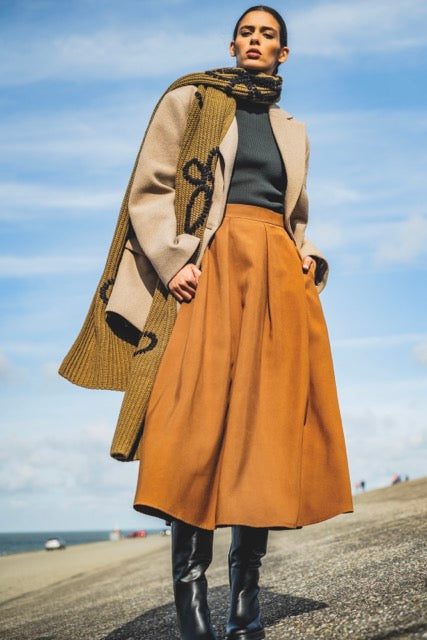 Woman wearing the Livia Skirt sewing pattern from Fibre Mood on The Fold Line. A skirt pattern made in cotton twill, poplin, viscose (crepe), lyocell or woollen fabrics, featuring a midi length, A-line silhouette, front and back pleats, side seam pockets