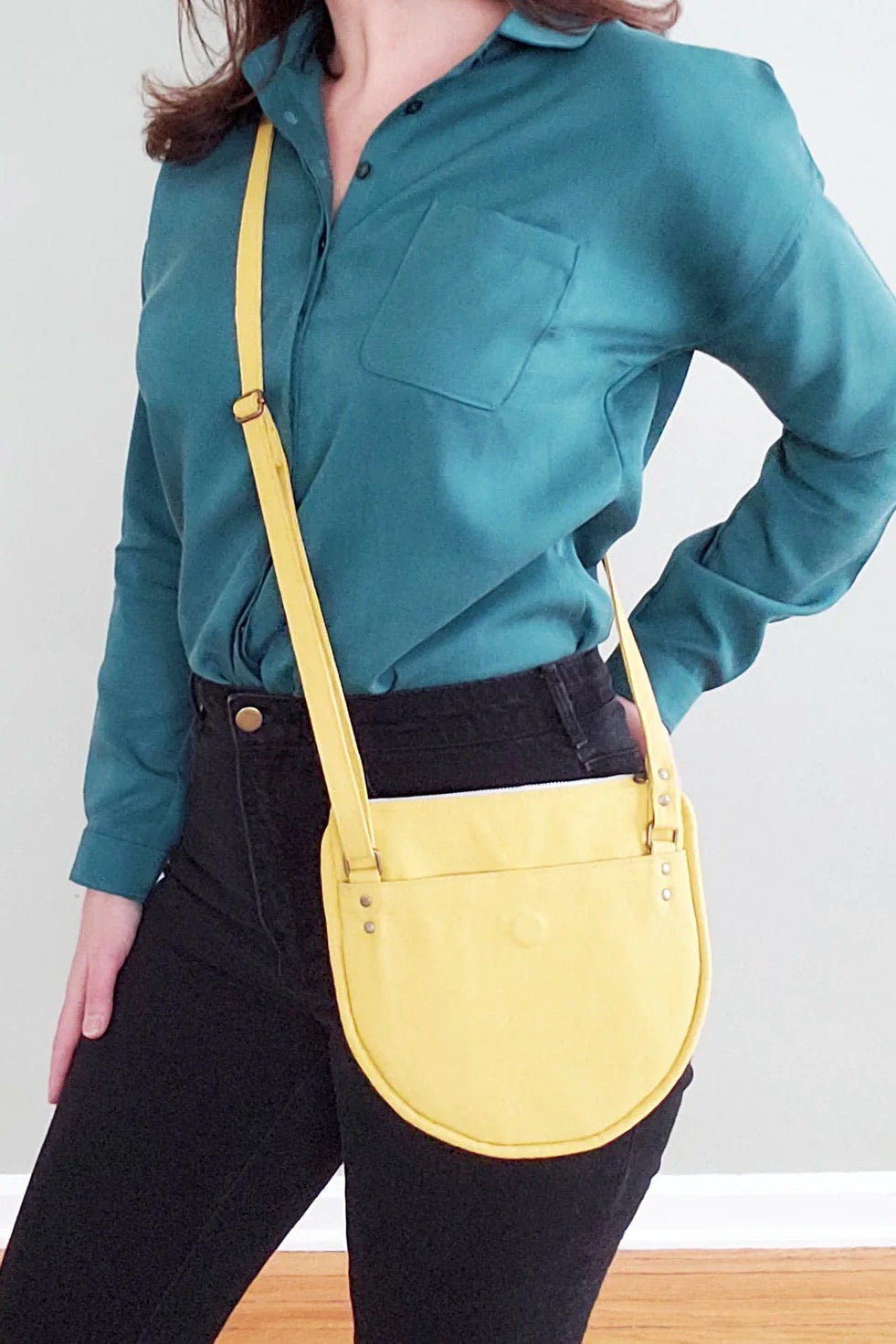 Woman wearing the Luna Crossbody Bag sewing pattern from Pattern Scout on The Fold Line. A bag pattern made in duck canvas, twill, bull denim, upholstery fabric, or waxed canvas, featuring a slim profile, six interior slip pockets, one exterior slip pocke