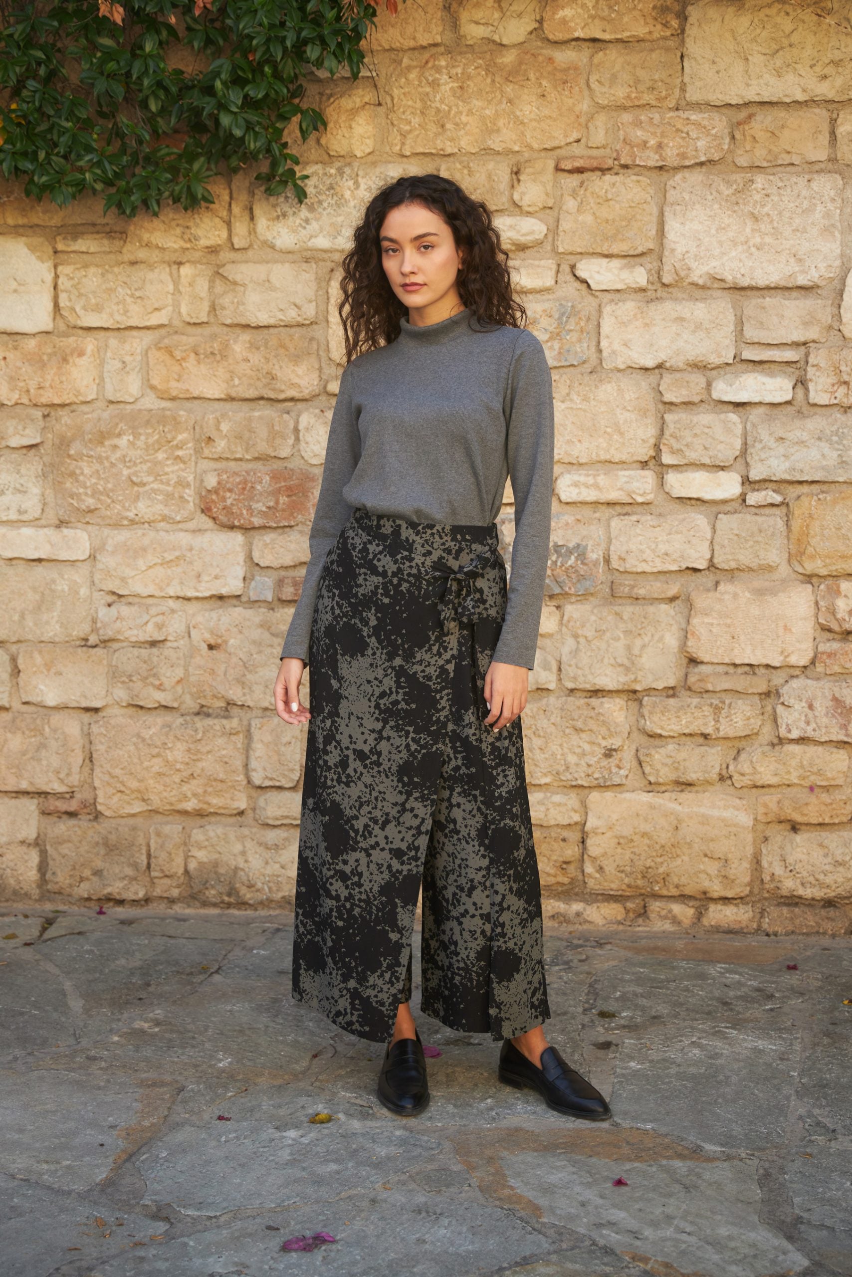 Woman wearing the Magnolia Pants sewing pattern from The Patterns Room on The Fold Line. A trouser pattern made in soft linen, viscose, light denim or crepe fabrics featuring a wide leg with extra front skirt layer tied at the left side, elasticated back