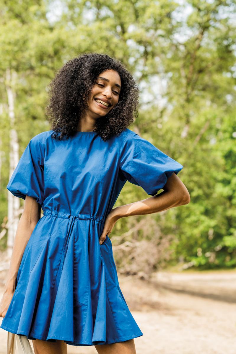 Woman wearing the Meryll Dress sewing pattern from Fibre Mood on The Fold Line. A dress pattern made in voile, poplin, broderie anglaise, chambray, silk (satin), lyocell, crepe or double gauze fabrics, featuring puff sleeves, round neckline, flared skirt