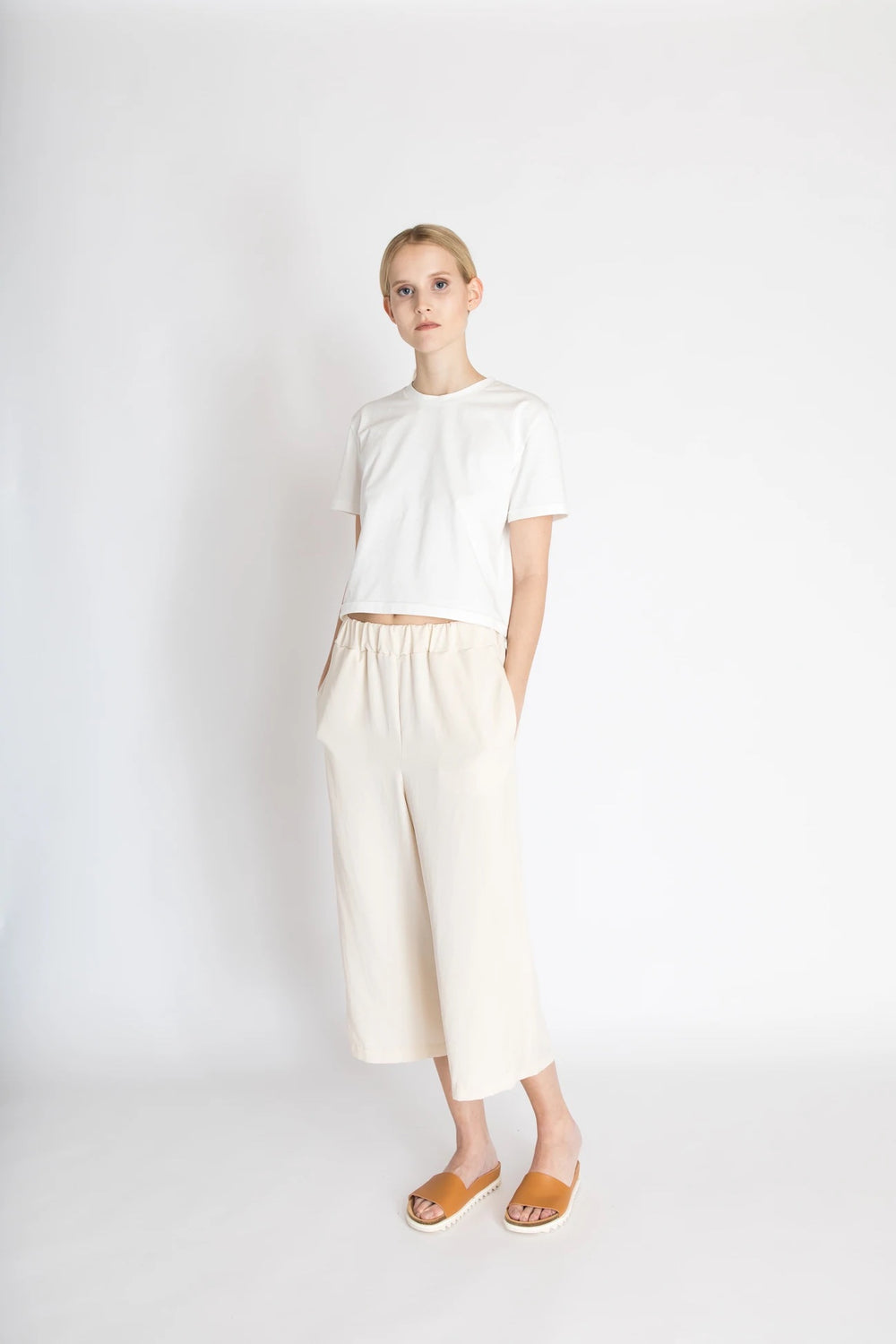Woman wearing the Nova Pants sewing pattern from Bara Studio on The Fold Line. A culottes pattern made in cotton, linen or tencel fabrics, featuring wide legs, relaxed fit, elasticated waist, back patch pocket, in-seam pockets, faux fly front and cropped