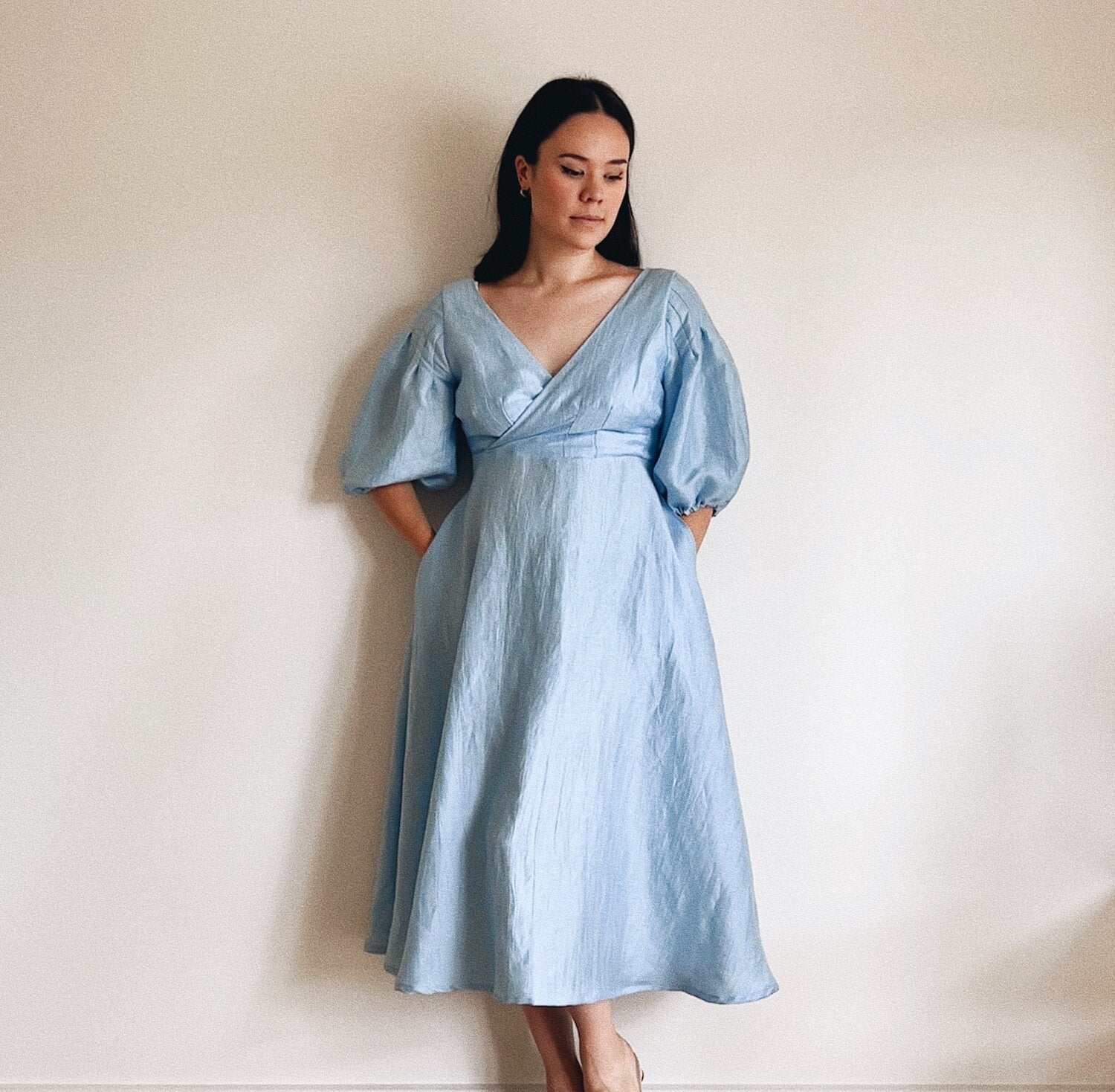 Woman wearing the Odette Dress sewing pattern from Veronica Tucker on The Fold Line. A dress pattern made in linen fabrics, featuring a faux-wrap, V-neck, bias cut, full circle skirt, bodice and sleeve darts, and midi length.