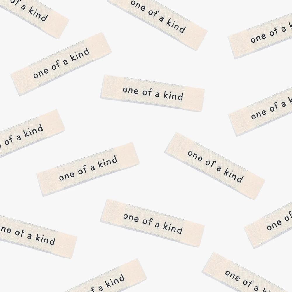 Photo showing 'One of a Kind' Woven Labels from Kylie & The Machine on The Fold Line. A washable, durable and non-scratchy fabric label featuring the words 'One of a Kind' all ready to be sewn into your handmade clothes.