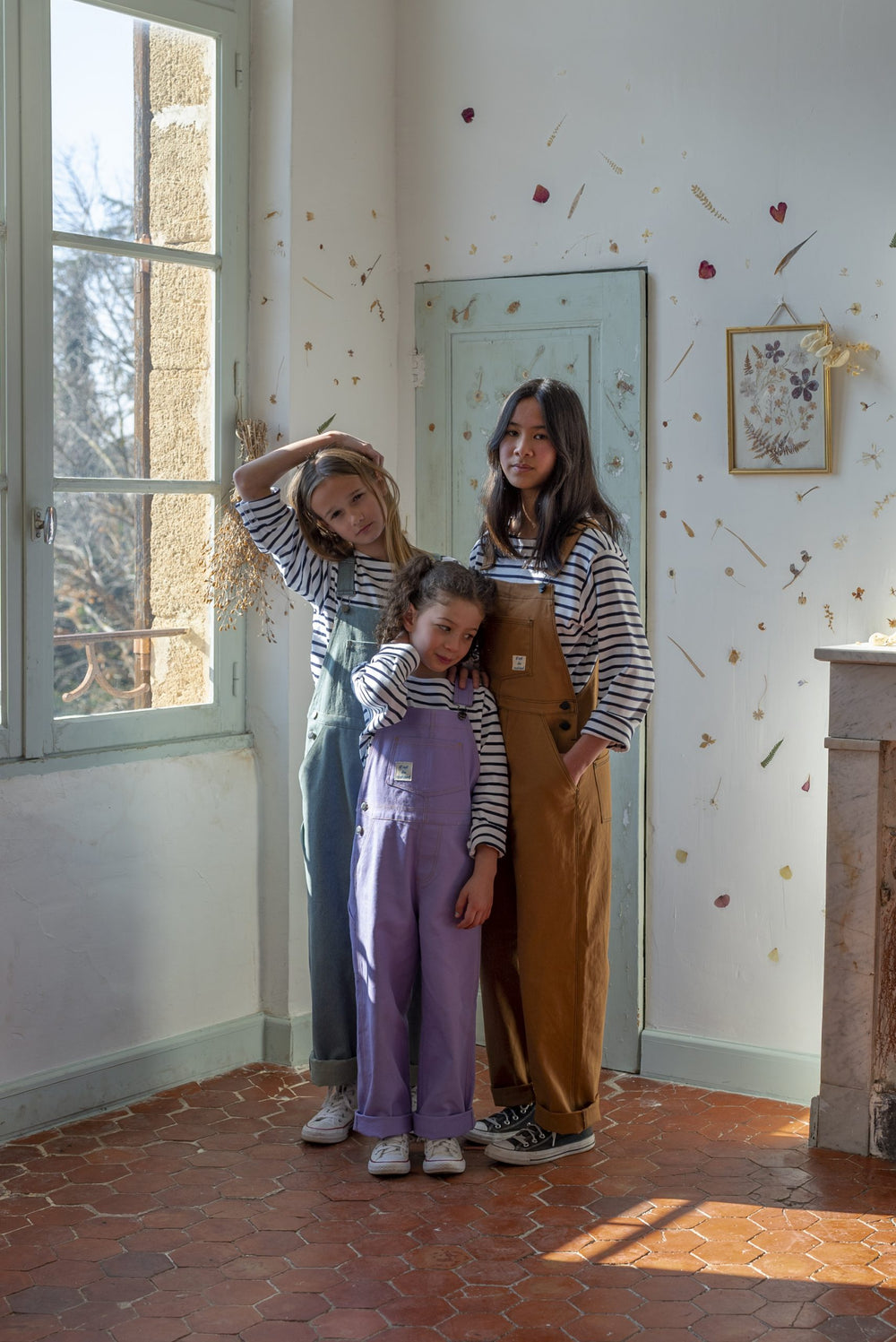 Children wearing the Penny Overalls sewing pattern from Ready to Sew on The Fold Line. A dungaree pattern made in denim, cotton canvas, or corduroy fabrics, featuring a relaxed fit, straight silhouette, multiple patch pockets, topstitching, side button cl