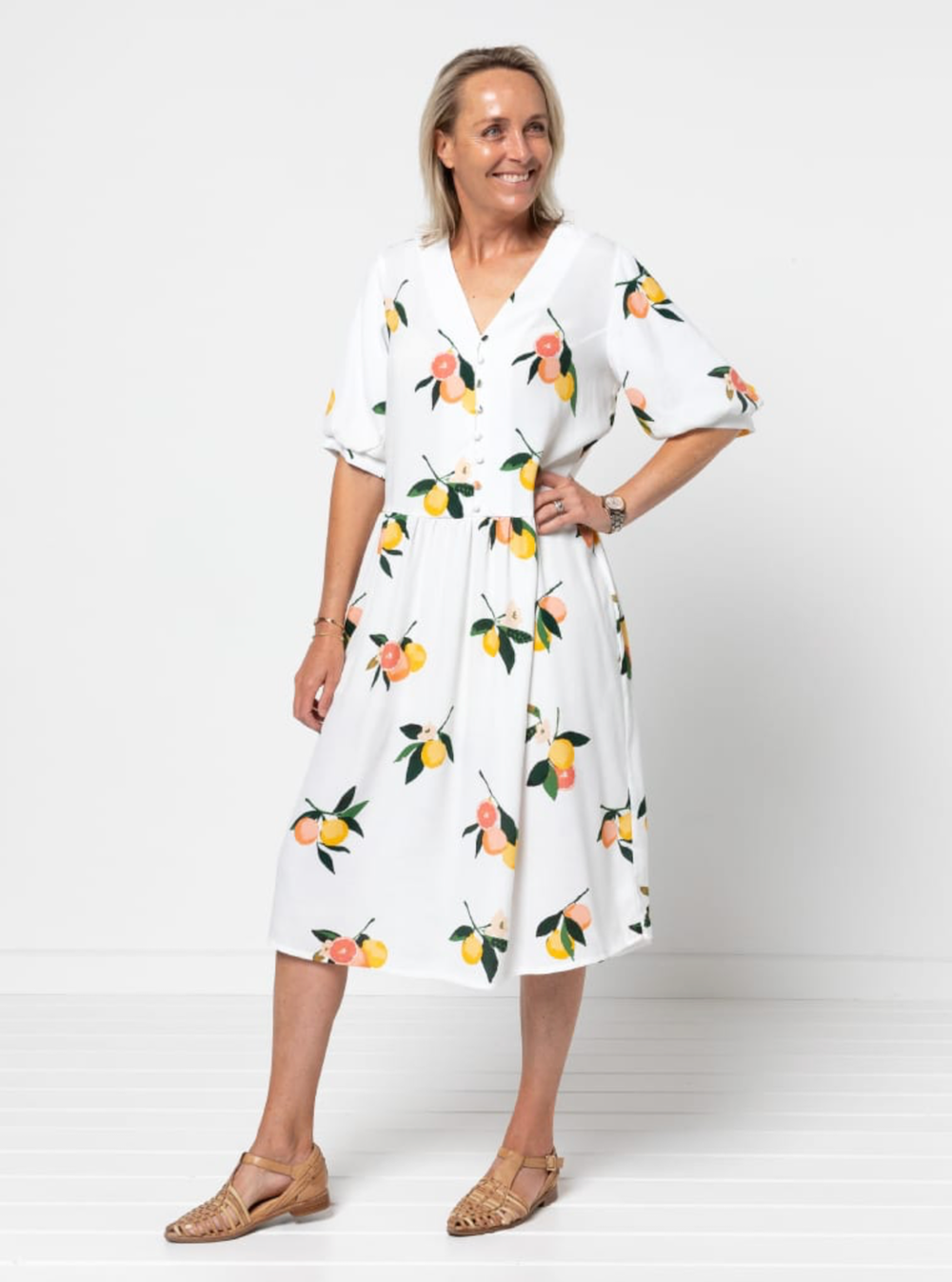 Woman wearing the Porter Woven Pack sewing pattern from Style Arc on The Fold Line. A dress pattern made in cotton, rayon, crepe, or washed linen fabric, featuring a v neck, button front bodice, mid-length sleeves, low waist, gathered skirt, in-seam pocke