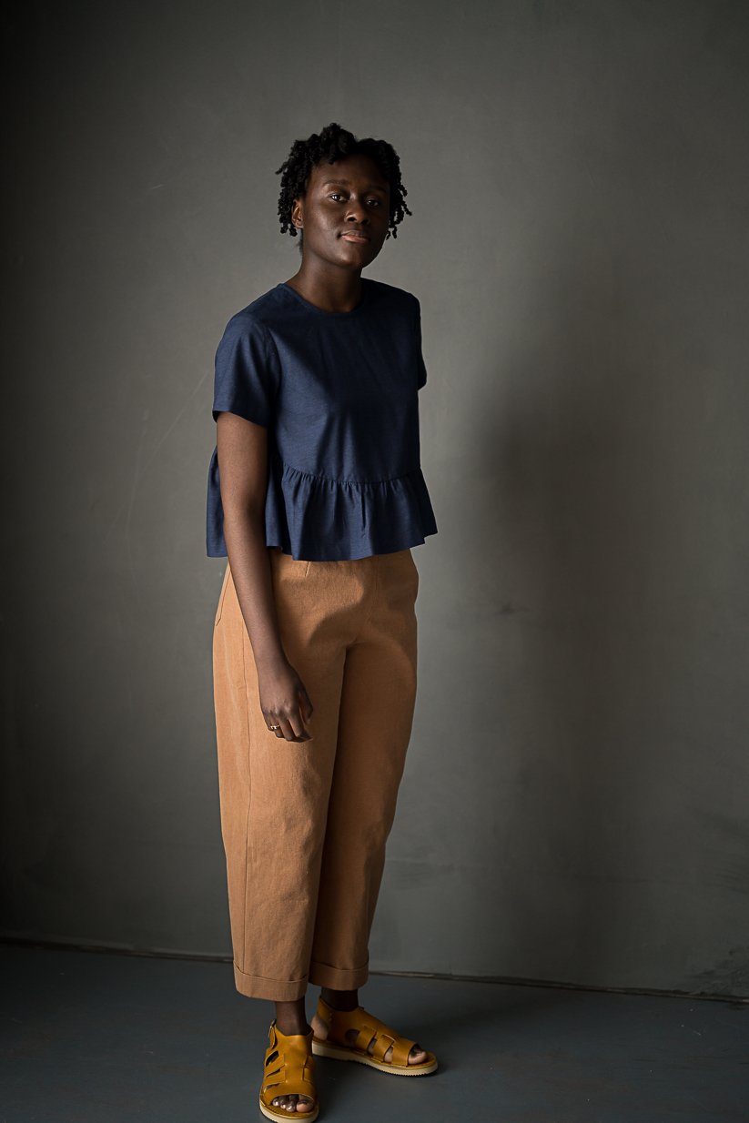 Woman wearing the Eve Trousers sewing pattern by Merchant and Mills. A trouser pattern made in cotton twill, denim, corduroy, woollens or linen fabric featuring a side zip, two back pockets, cropped length, slightly tapered shape and turn ups.