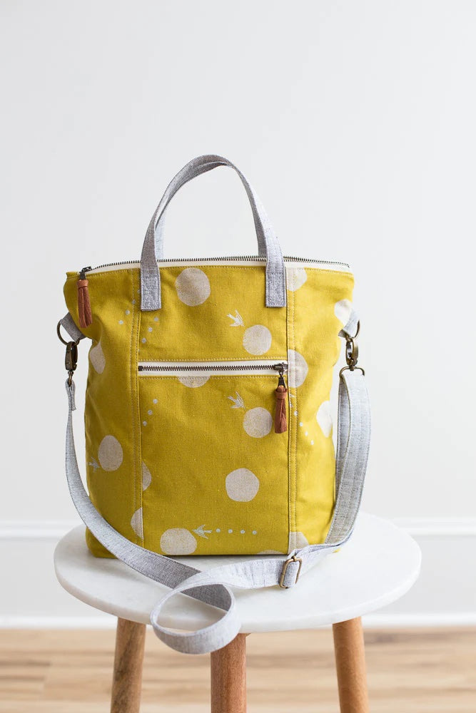 Photo showing the Redwood Tote sewing pattern from Noodlehead on The Fold Line. A tote pattern made in canvas or waxed canvas fabrics, featuring a medium size, adjustable crossbody strap, front zippered pocket, back slip pocket, interior slip pocket, zip