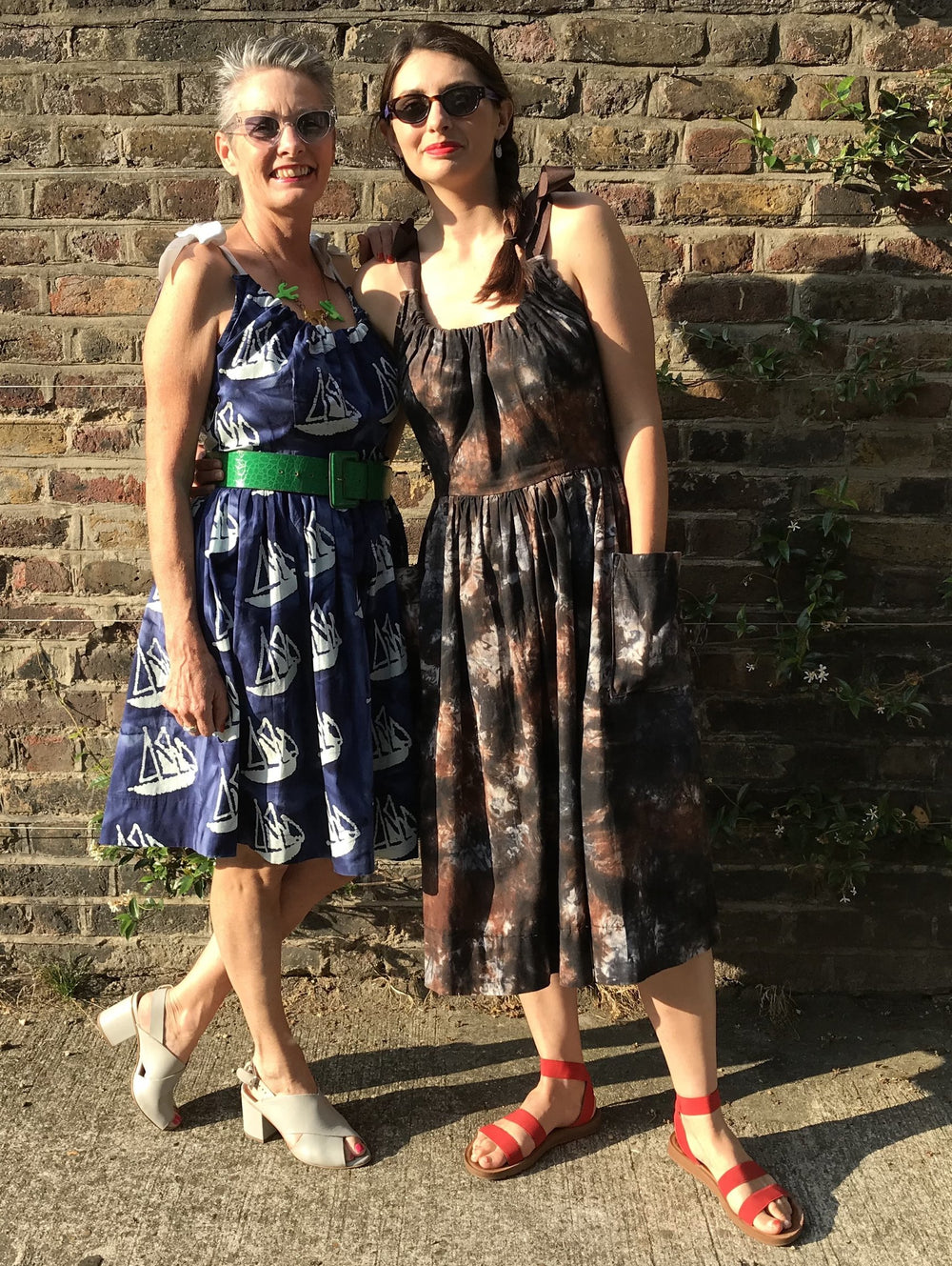 Women wearing the Regatta Dress sewing pattern by Alice and Co Patterns. A sleeveless, dress pattern made in cotton, seersucker, lightweight denim, cotton shirting or African waxed cotton fabrics, featuring a gathered shirt, patch pockets, knee or midi le