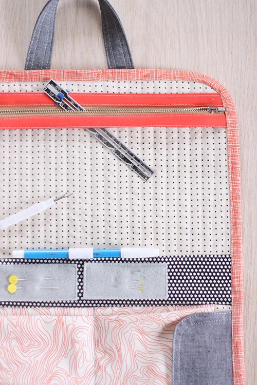Photo showing the Road Trip Case sewing pattern from Noodlehead on The Fold Line. A small carry case pattern made in denim, canvas, twill or quilting cotton fabrics, featuring 4 pockets with Velcro flaps, see-through vinyl pocket with zip closure, button