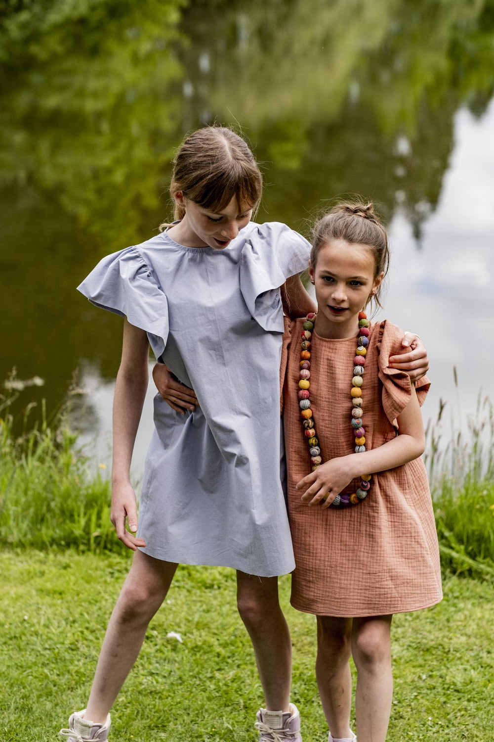 Children wearing the Children's Sunny Dress sewing pattern from Fibre Mood on The Fold Line. A dress pattern made in poplin, chambray, lyocell, double gauze, crepe, satin, embroidery, lace, jacquard, seersucker fabrics, featuring a ruffled short sleeve, d