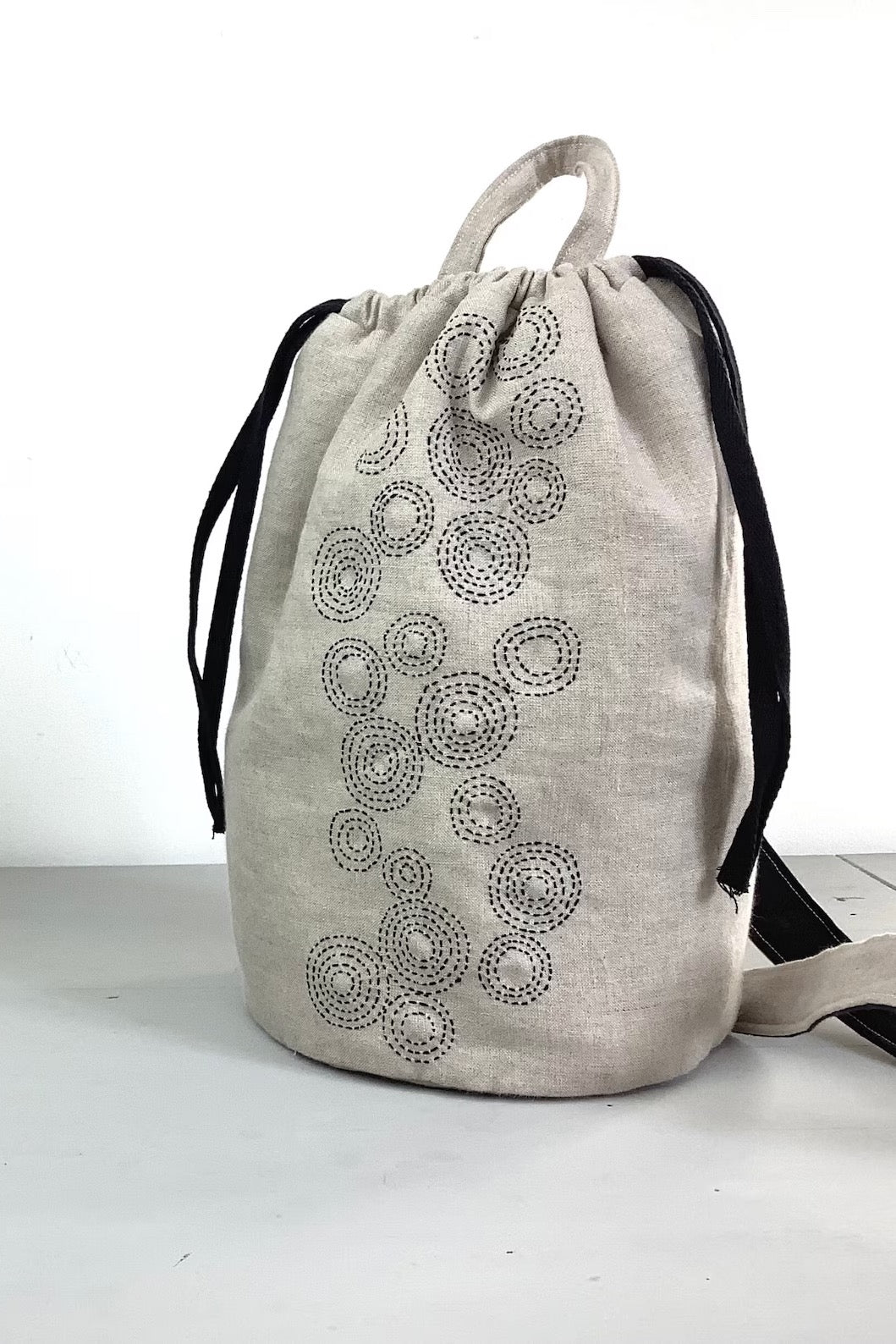 Photo showing the Taru Maru Crossbody Duffle Bag sewing pattern from Lasenby on The Fold Line. A duffle bag pattern made in canvas, linen, quilting cotton, twill, duck, denim, fine tweed, and Tana lawn fabrics, featuring a sashiko hand embroidery design,